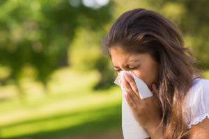 person in a park sneezing into a tissue